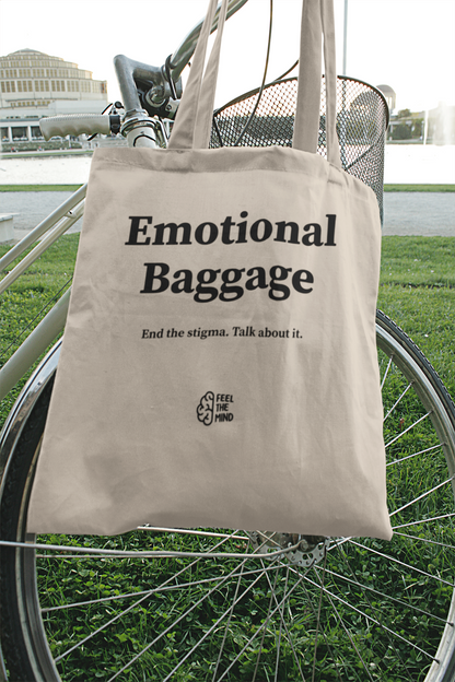 Natural colored tote bag with "emotional baggage" on it hanging from a bicycle
