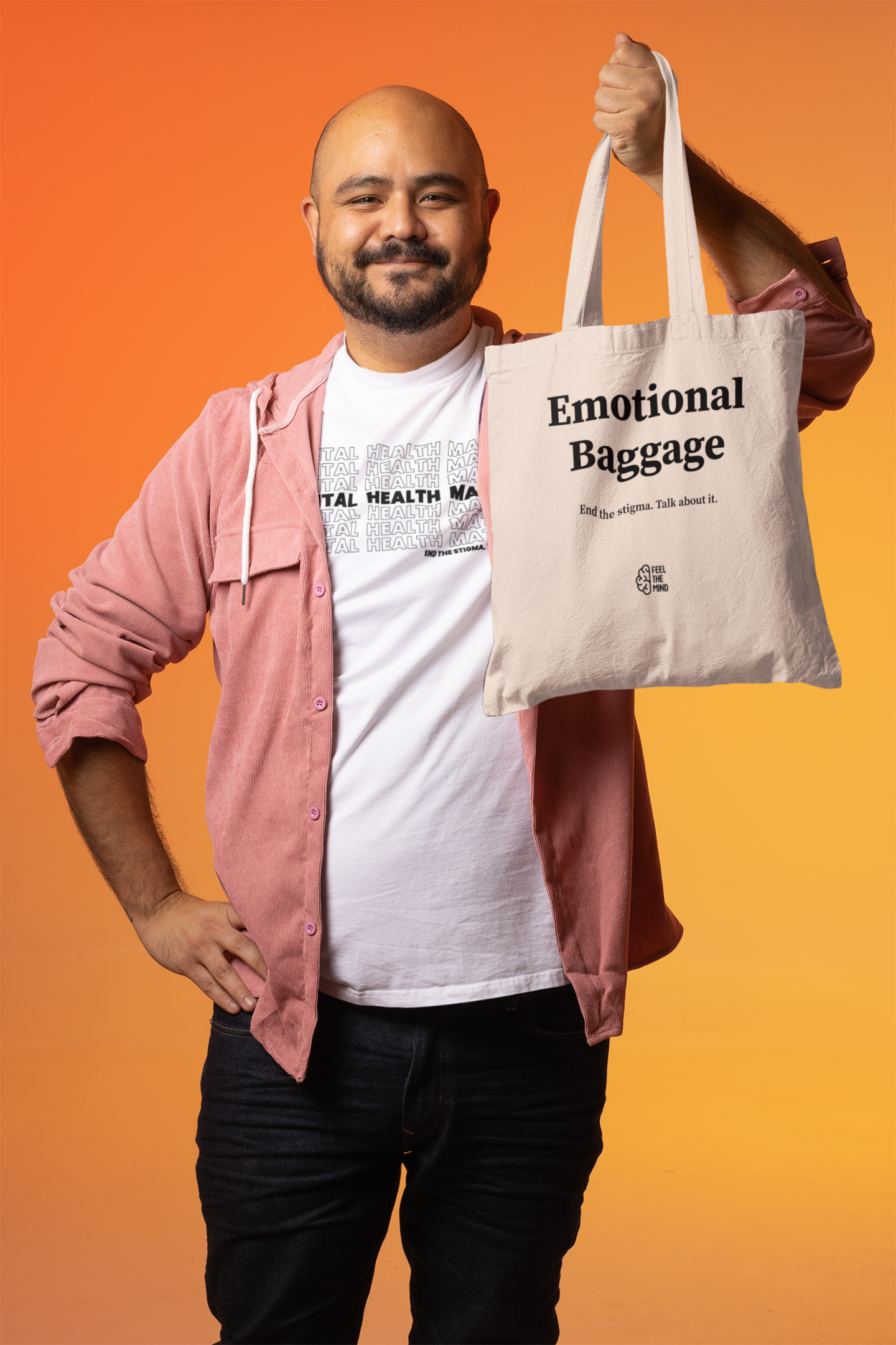 Man wearing a mental health matters shirt while holding an emotional baggage tote bag in his left hand