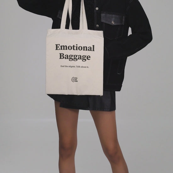 Woman holding a tote bag that says "Emotional Baggage"